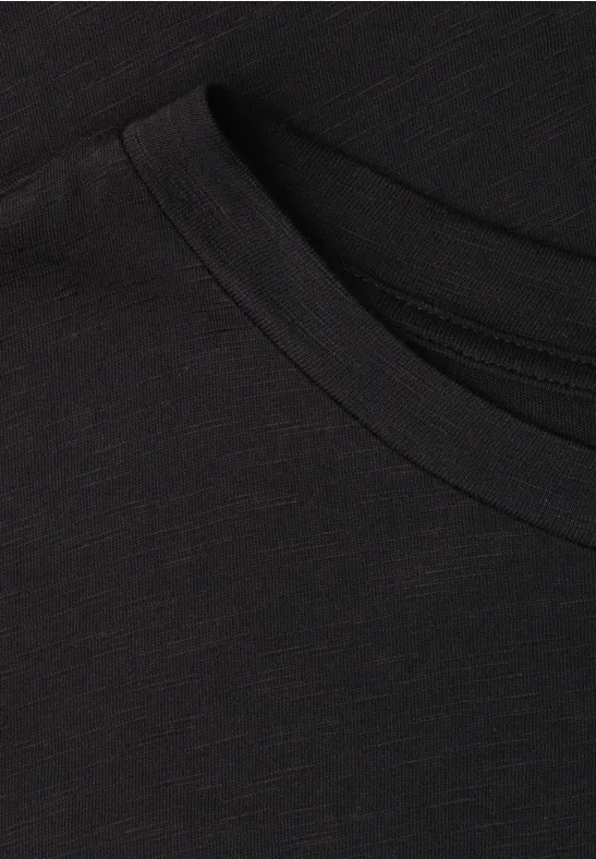 Nahaufnahme eines schwarzen T-Shirts, Fokus auf Rundhalsausschnitt und feine Stoffstruktur.