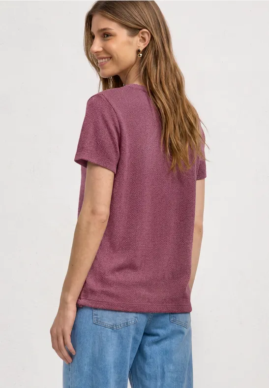 Vrouw van achteren in een paars t-shirt en blauwe jeans, casual outfit.