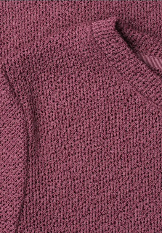 Close-up van een rosé grofgebreide trui.