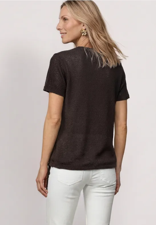 Vrouw van achteren in zwart t-shirt en witte broek, halflang blond haar.