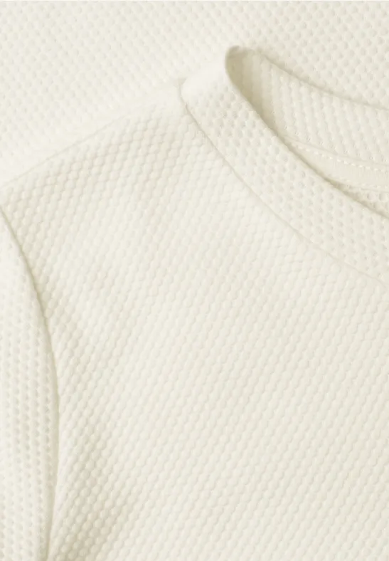 Nahaufnahme eines weißen Shirts mit feiner Wabenstruktur im Stoff.