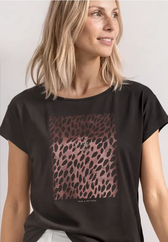 Frau in schwarzem T-Shirt mit braunem Leopardenmuster auf der Brust.