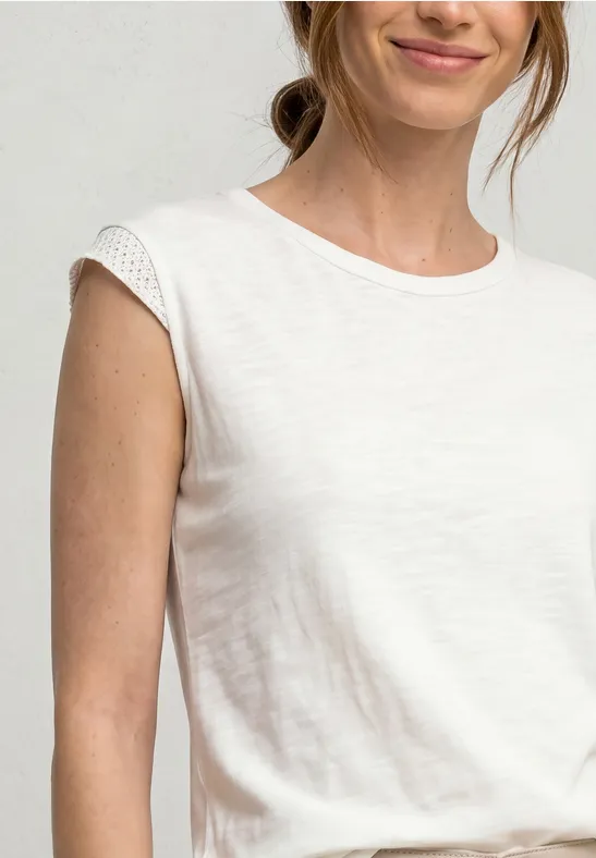 Eine Frau in einem weißen, lockeren, kurzärmligen T-Shirt, Ausschnitt bis zur Taille sichtbar.