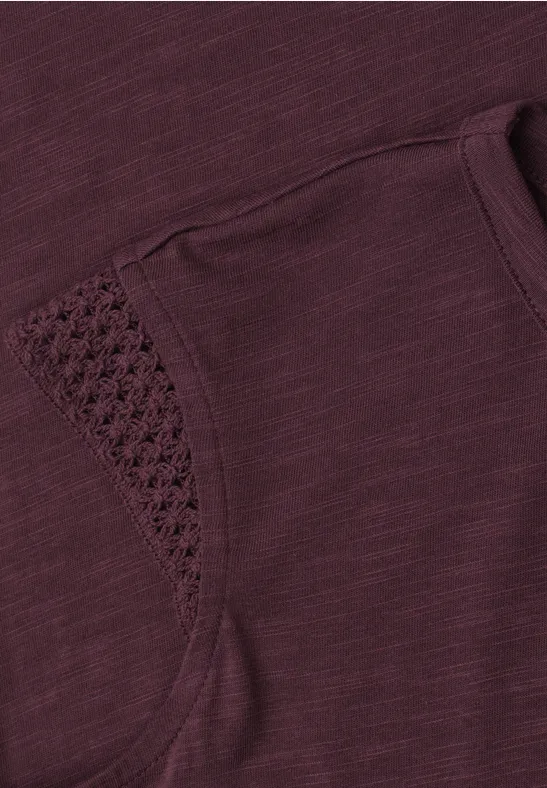 Close-up van paarsachtig shirt met zakje en verfijnde gehaakte rand.