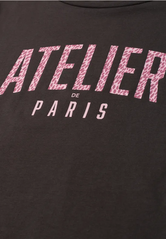 T-shirt noir avec inscription rose 'ATELIER de PARIS'.