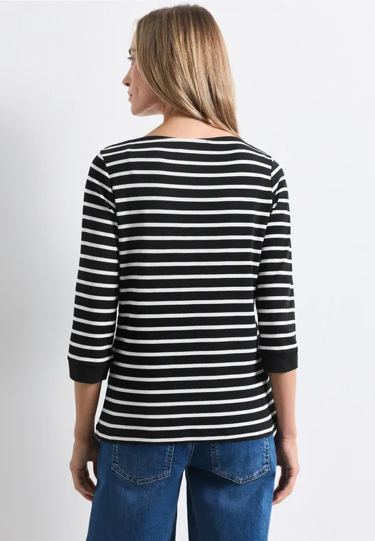 Frau von hinten in schwarzem, weiß geringeltem 3/4-Arm-Shirt und blauen Jeans.