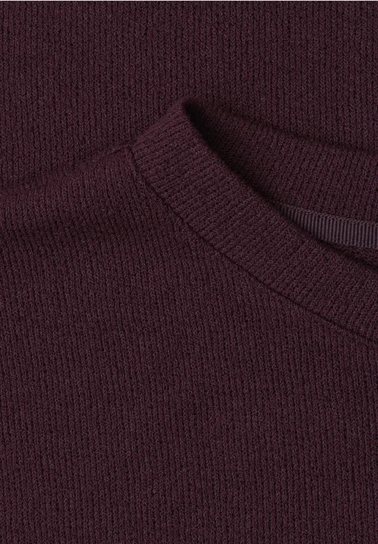 Nahaufnahme eines dunkelvioletten Strickpullovers mit Rundhalsausschnitt.