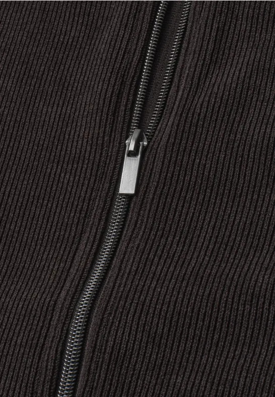Close-up van een zwarte metalen rits op donker ribfluweel.
