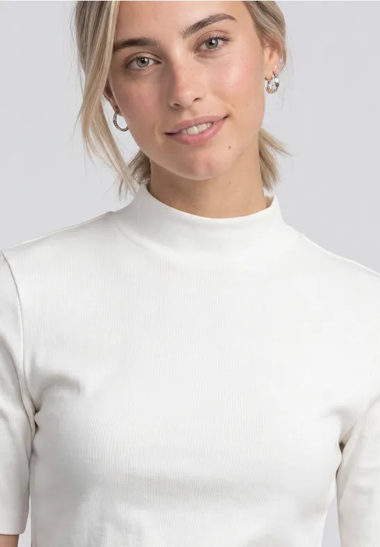 Junge Frau mit blondem Pferdeschwanz, dezentem Lächeln und weißem, kurzärmligem Rollkragenpullover.