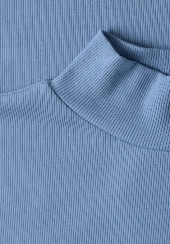 Nahaufnahme eines hellblauen, fein gerippten Rollkragenpullovers.