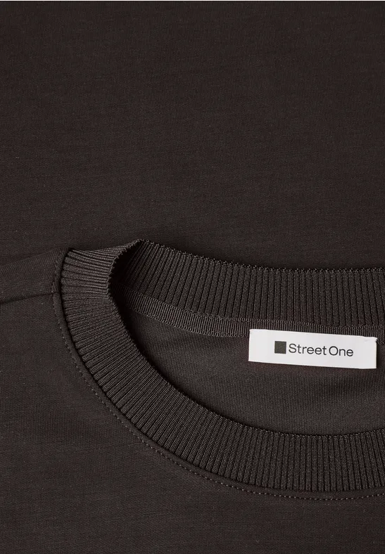 Nahaufnahme eines schwarzen T-Shirts mit Rundhalsausschnitt und 'Street One'-Etikett im Nacken.