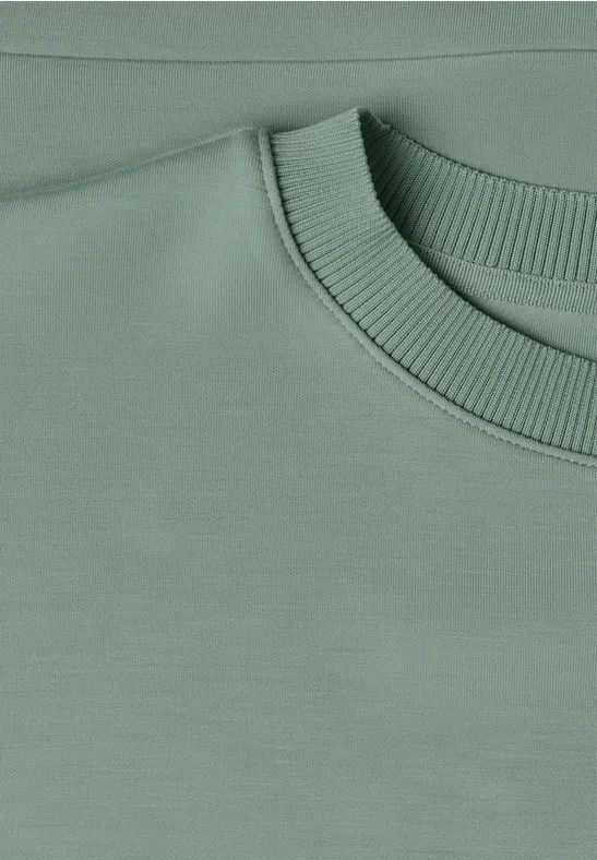 Close-up van een pastelgroene sweater met geribbelde ronde hals.