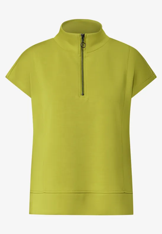 Hellgrünes Damen-Shirt mit Stehkragen, kurzem Arm und halbem Reißverschluss.