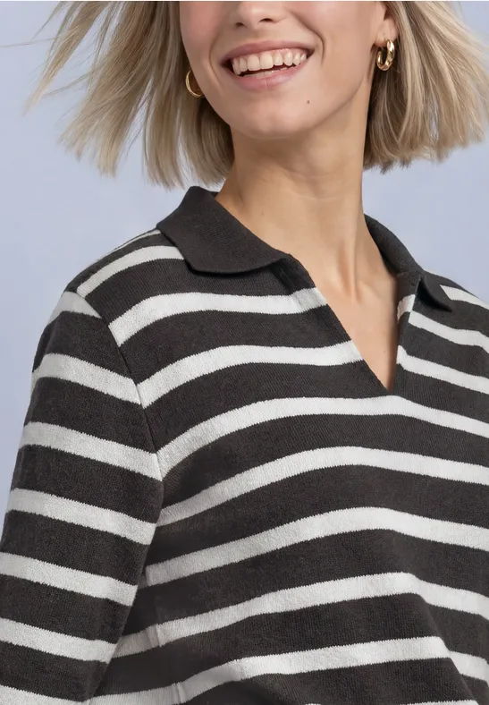 Frau mit blondem Bob und gestreiftem schwarz-weißem Poloshirt lächelt