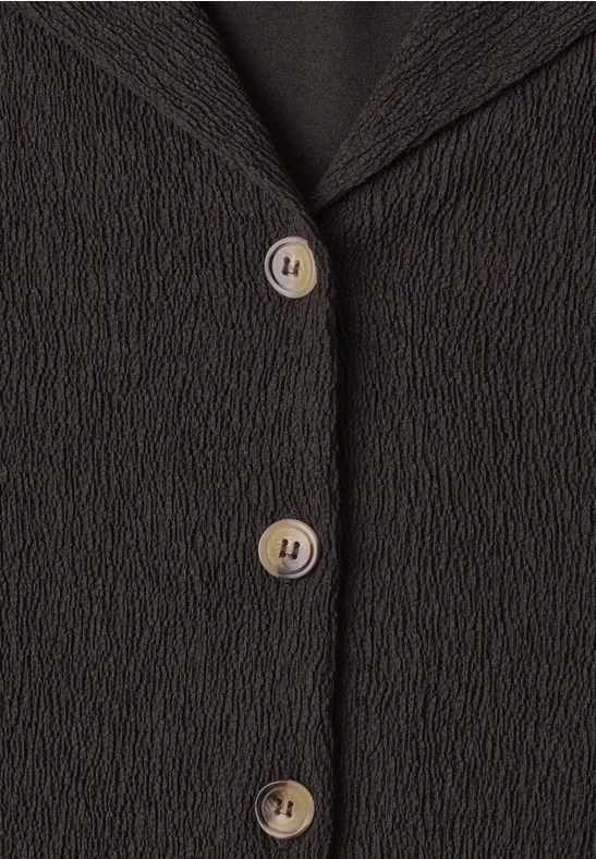 Vorderseite eines schwarzen, strukturierten Blazers mit drei cremefarbenen Knöpfen.
