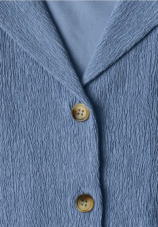 Makroaufnahme einer blau strukturierten Jacke mit zwei runden Holzknöpfen.