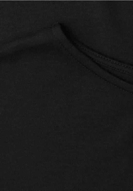 Nahansicht eines schwarzen Kleidungsstücks aus Baumwollstoff mit sichtbarer Naht und Tasche.
