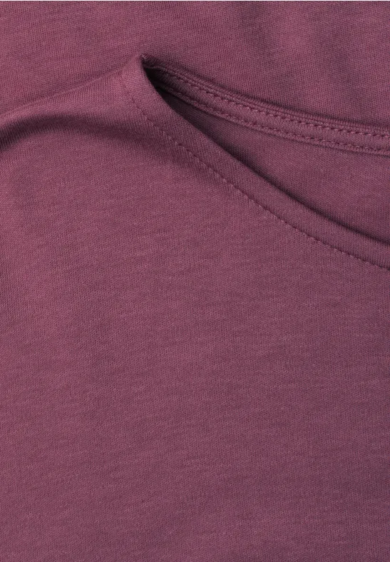 Nahaufnahme eines beerenfarbenen Baumwollshirts mit einem schräg angesetzten Einschubtaschendetail.
