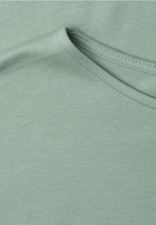 Close-up einer hellgrünen Baumwoll-T-Shirt-Partie mit Rundhalsausschnitt und feiner Naht