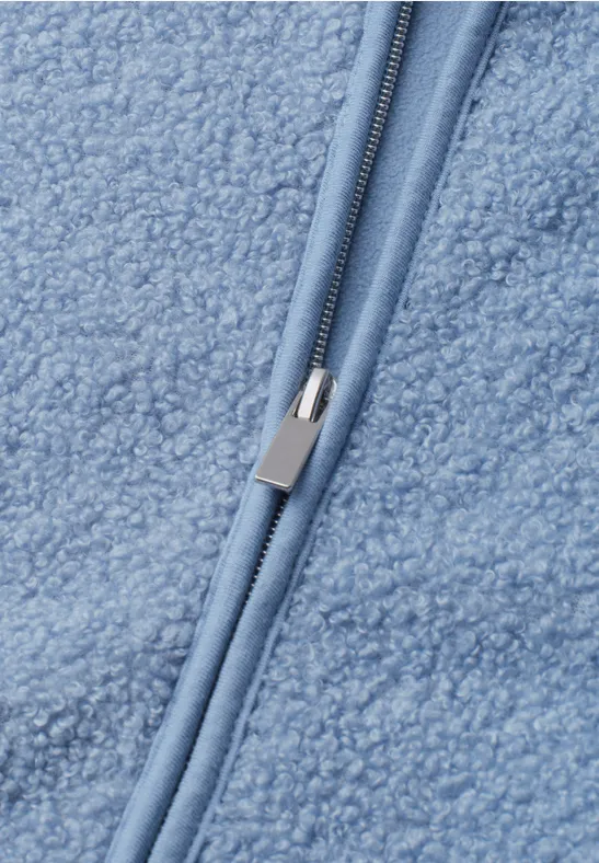 Nahaufnahme eines hellblauen Sherpa-Fleecestoffes mit Reißverschluss.