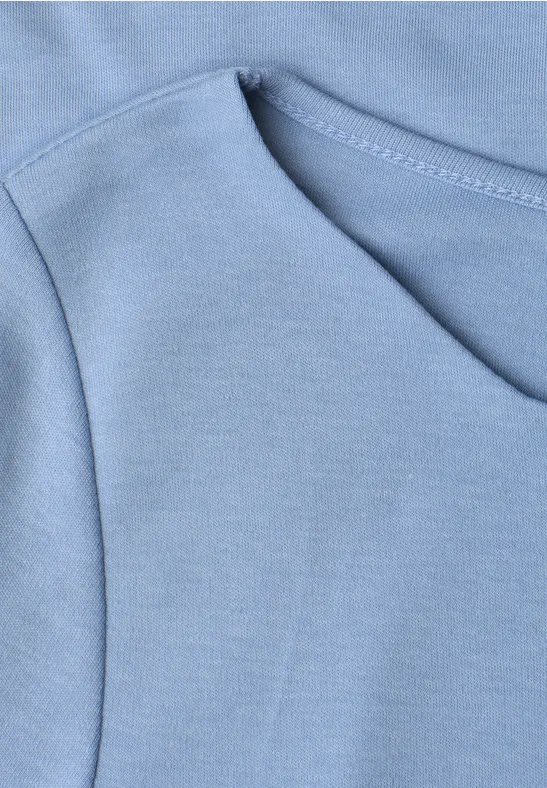 Nahaufnahme einer hellblauen Kapuzenpullover-Tasche mit sichtbaren Nähten.