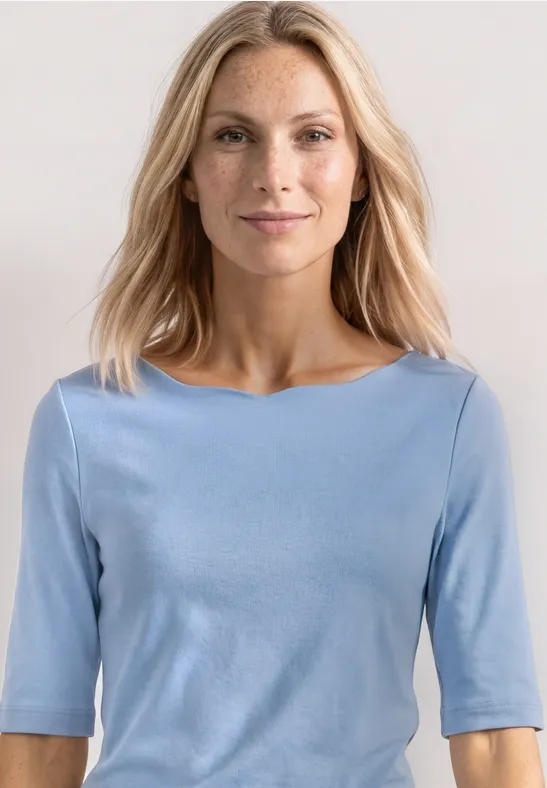 Frau in hellblauem Halbarmshirt vor neutralem Hintergrund