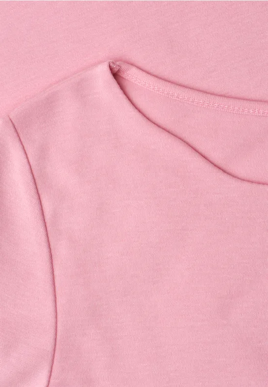 Close-up van een roze T-shirt met ronde hals en zichtbare naden.