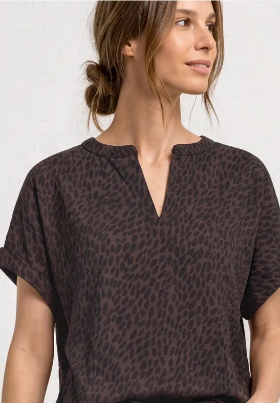 Kobieta w ciemnym topie z krótkimi rękawami, subtelnym animal print i dekoltem w serek.