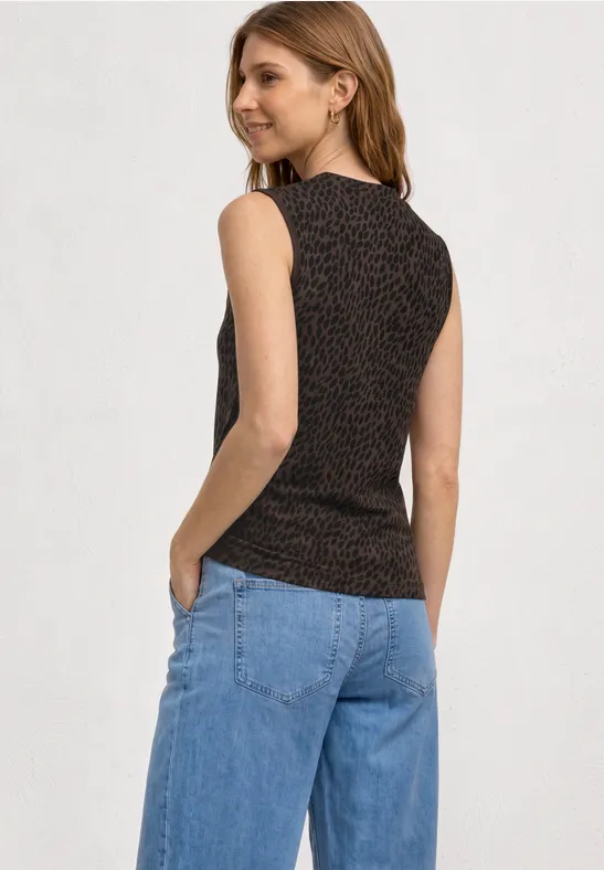 Rückansicht einer Frau in ärmellosem, gemustertem Top und blauen Jeans vor weißem Hintergrund.