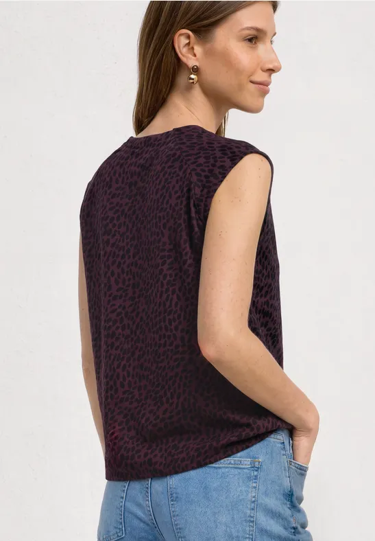 Raglan-Oberteil ohne Ärmel mit dezentem Leopardenmuster in Dunkellila, kombiniert mit hellblauen Jeans.