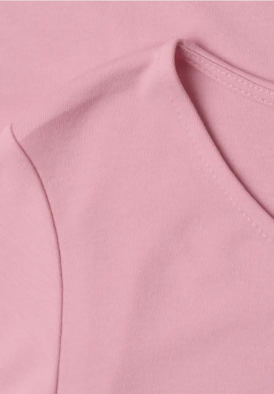 Nahaufnahme eines rosa T-Shirts aus weichem Stoff mit sichtbarer Naht und Rundhalsausschnitt.