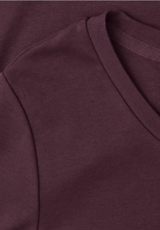 Nahaufnahme eines burgunderfarbenen T-Shirts mit V-Ausschnitt.