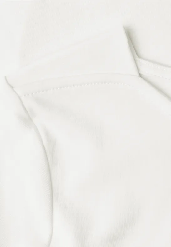 Nahaufnahme eines weißen Baumwollshirts, das den oberen Ausschnitt und die Schulterpartie zeigt.