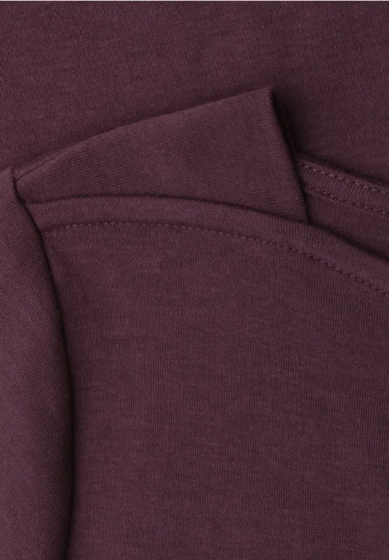 Detailaufnahme eines weinroten Baumwoll-T-Shirts mit Rundhalsausschnitt und feiner Naht.