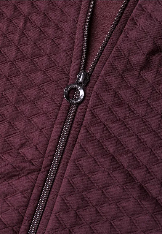Dunkelrote, gesteppte Jacke mit sichtbar gewebter Struktur und Metallring am Reißverschluss.