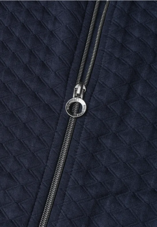 Gestepptes, dunkelblaues Textil mit mittig platziertem Reißverschluss und rundem Zipper-Anhänger.
