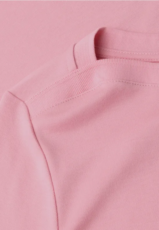 Nahaufnahme eines pastellrosa T-Shirts mit sichtbarer Schulternaht.