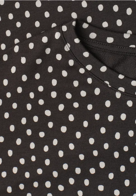 Schwarzes Kleidungsstück mit weißem Polka-Dot-Muster.