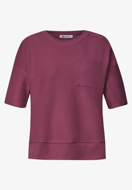Un t-shirt à manches courtes bordeaux avec encolure ronde et poche poitrine.