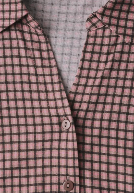 Nahaufnahme einer rosa-schwarzen karierten Bluse mit Knopfverschluss.