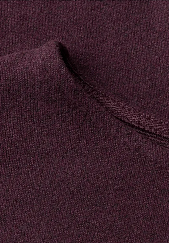 Nahaufnahme eines weinroten Strickpullovers mit sichtbarer Naht