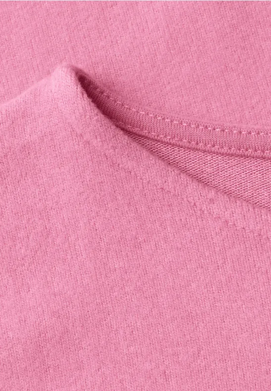 Close-up van de halslijn van een roze T-shirt van zachte stof.