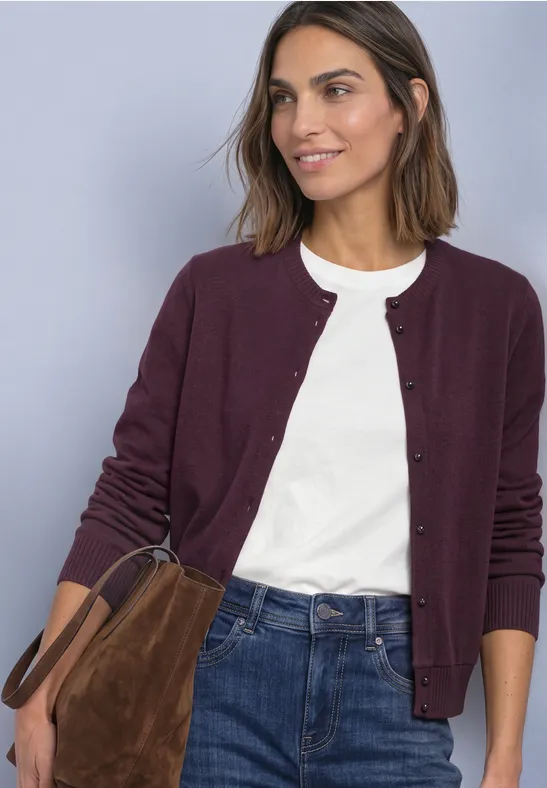 Femme portant un t-shirt blanc, un gilet bordeaux, un jean bleu et un sac à main marron en daim