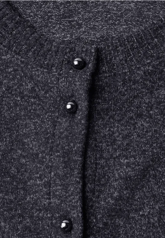 Nahaufnahme eines grauen Strickcardigans mit schwarzen Kugelknöpfen.