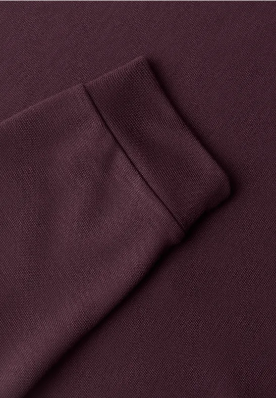 Nahaufnahme eines burgunderroten Sweatshirt-Ärmels mit Rippbündchen