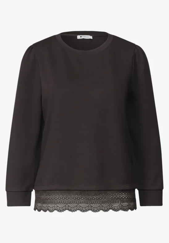 Schwarzer Pullover mit Rundhalsausschnitt, langen Ärmeln und Spitzenbesatz am Saum.