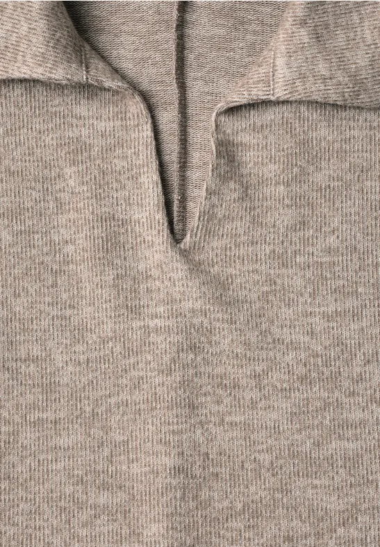 Nahaufnahme eines beige-grauen Strickpullovers mit V-förmigem Ausschnitt und aufgestelltem Kragen.