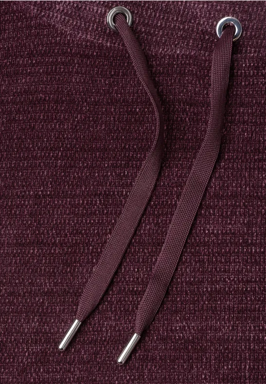 Close-up van bordeauxkleurige gebreide stof met twee capuchonkoorden.