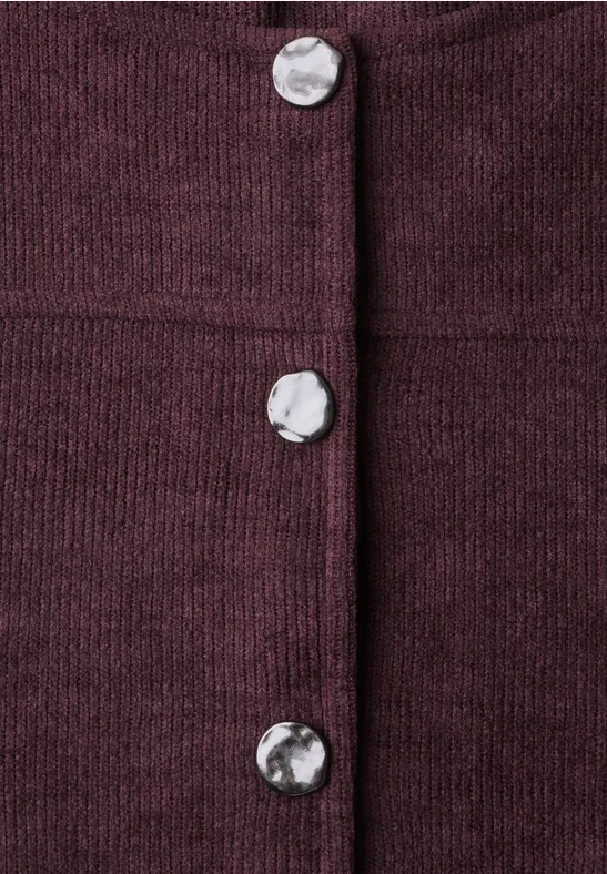 Close-up eines burgunderfarbenen Strickstoffs mit auffälligen silbernen Knöpfen.