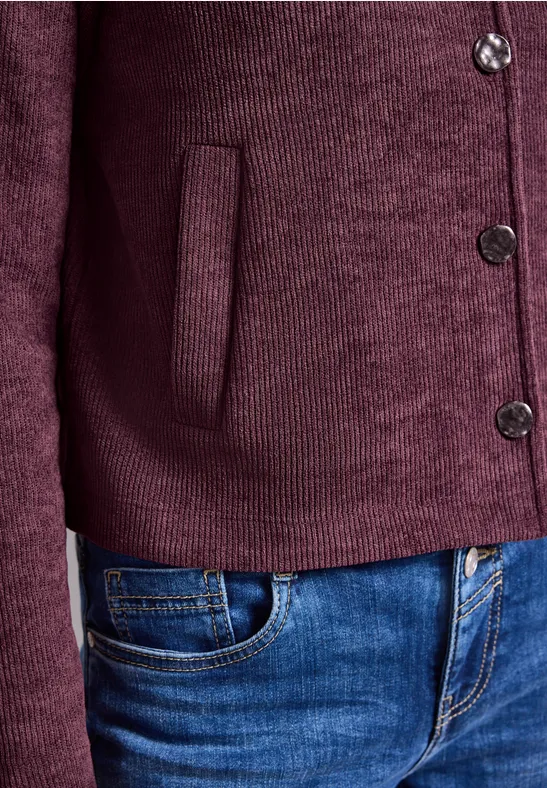 Dunkelroter Strickcardigan mit Knöpfen und Tasche, kombiniert mit blauen Jeans.
